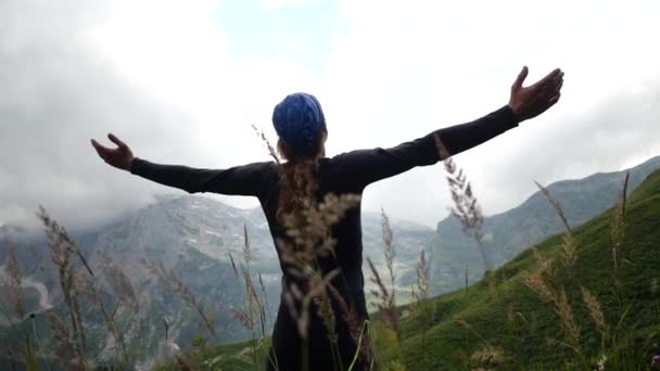 Hombre excursionista con el pelo largo levanta las manos en las montañas disfrutando de una hermosa vista y la naturaleza salvaje circundante. Victoria y éxito, el logro de la meta . — Vídeos de Stock