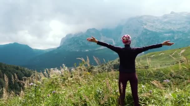 Mujer excursionista levanta las manos en las montañas disfrutando de una hermosa vista y la naturaleza salvaje circundante. Victoria y éxito, el logro de la meta . — Vídeos de Stock