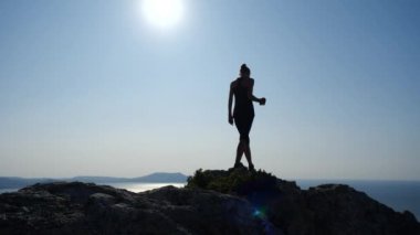 Bir fincan çay ile zirvede duran ve güzel mavi gökyüzüne karşı bir deniz üzerinde bir hight fantastik görünümü zevk mutlu bir yürüyüşçü kadın Siluet.