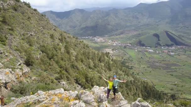 Letecký pohled na mladého páru na horském hřebeni mávající ruce. Úžasná horská krajina na Tenerife, Kanárské ostrovy. — Stock video