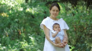 Bir parkta yeşil çimenlerin üzerinde yeni doğmuş kızıyla birlikte anne. Mutlu genç Anne ve Çocuk sarı çiçek ile oynamak. Bahar parkında doğanın tadını çıkaran güzel aile.