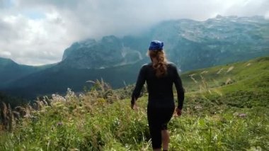 Dağlarda uzun saçlı adam yürüyüşçü kayalık kayalıklar, buzul ve karlı zirvelere karşı güzel manzara ve çevreleyen dağ çayırları zevk ellerini kaldırır.