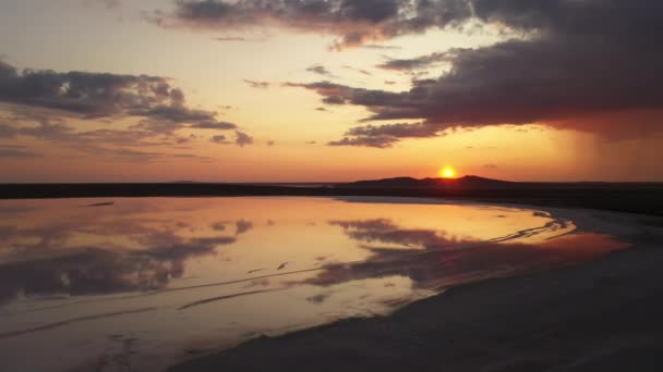 Drone aéreo tiro de um lago salgado na Crimeia ao pôr-do-sol dramático. Nascer do sol deslumbrante sobre o lago Koyashsky sal. paisagem plana com montanha no horizonte. chuva caindo de uma nuvem no fundo . — Vídeo de Stock