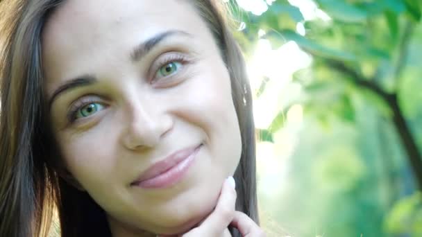 Close up retrato de Jovem morena sorrindo. Mulher bonita com o cabelo soprando no vento olhando para a câmera — Vídeo de Stock