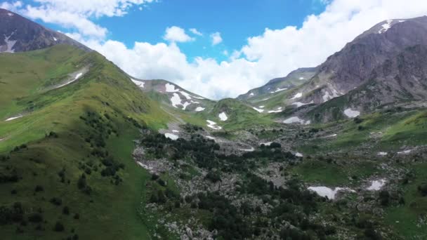 아디게아, 계곡, 산등성이의 산악 패스의 공중 전경. 바위와 눈밭 사이 녹색 나무와 덤불. 위에서 본 야생의 자연. — 비디오