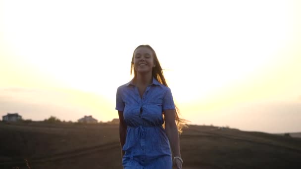 Happy young feminine girl runs on a background of sunny sunset. Her long silky hair flutters in the wind, she smiles and treads on air. Female natural beauty in slow motion. — Stock Video