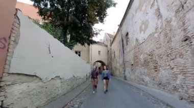 Vilnius'un dar sokaklarında yürürken konuşan ve gülen iki genç kadın.
