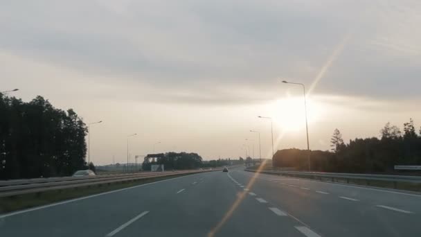 POV jazdy wzdłuż szerokiej pustej drogi porannej wcześnie rano podczas wschodu słońca.. Punkt widzenia jazdy, widok z wnętrza samochodu na autostradę w Polsce. — Wideo stockowe