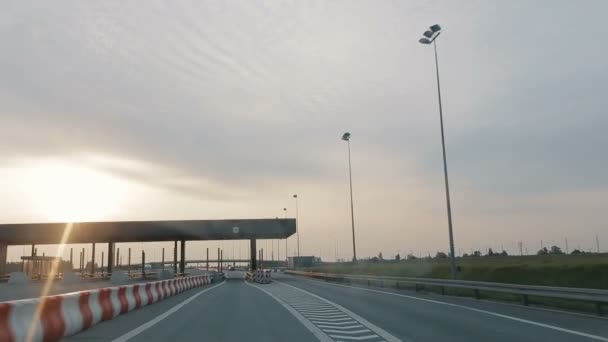 In den frühen Morgenstunden bei Sonnenaufgang über eine breite, leere Straße fahrend, Blick aus dem Auto auf die Autobahn in Polen. Ein- oder Ausfahrt in einen mautpflichtigen Straßenabschnitt. — Stockvideo