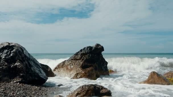 Grandes olas están cayendo sobre piedras y rociando en cámara lenta. Hermosa playa en Crimea con piedras y arena , — Vídeos de Stock