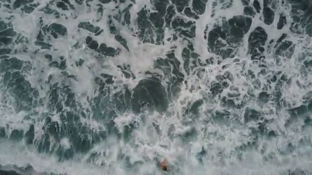 Vista aerea dall'alto di una donna che cammina su una spiaggia di sabbia nera di Tenerife, Spagna. Le onde dell'oceano si rompono e creano schiuma bianca su una sabbia nera, Isole Canarie . — Video Stock