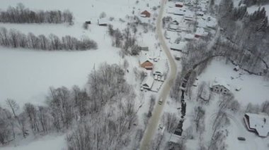 Karpat köyünde kış yolunda hareket eden bir arabanın havadan görünümü. Karla kaplı evlerin kuş bakışı görünümü. Kışın kırsal peyzaj.