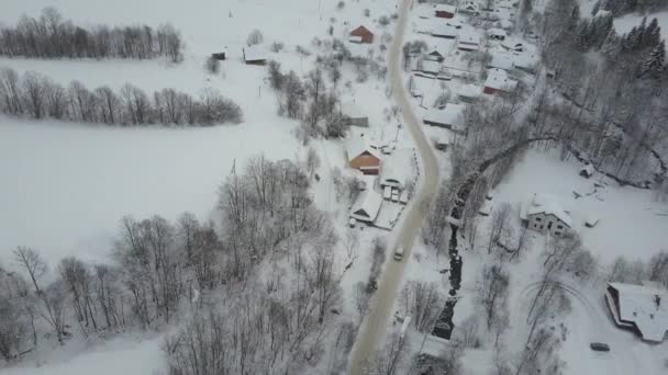 Vista aérea de un coche que se mueve en la carretera de invierno en la aldea de los Cárpatos. Vista de aves de casas cubiertas de nieve. Paisaje rural en invierno . — Vídeos de Stock