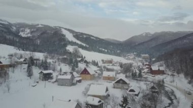 Kayak merkezi Pilipets için Karpat köyünde kış yolu üzerinde hareket eden bir araba havadan görünümü. Karla kaplı evlerin kuş bakışı görünümü. Kışın kırsal peyzaj.