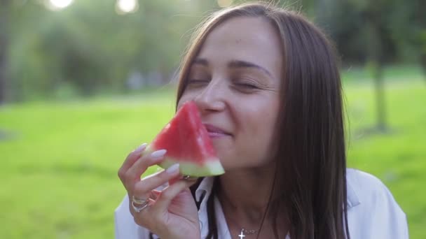 Ritratto ravvicinato di ragazza che odora l'aroma e mangia un cocomero succoso rosso sano, ingannando e ridendo su uno sfondo verde. Frutta: i benefici dei cibi verdi e un'alimentazione sana e naturale . — Video Stock