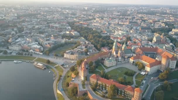 Vista aérea da Catedral Real de Wawel e castelo em Cracóvia, Polônia, com o rio Vístula, parque, quintal e turistas ao pôr-do-sol. Cidade velha no fundo — Vídeo de Stock