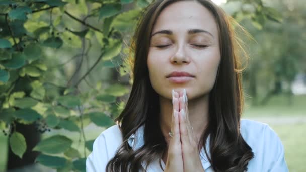 Niña ora a Dios en la religión cristiana o católica. La mujer dobló las manos y cerró los ojos en oración con fe. Retrato en cámara lenta de un estudiante creyente rezando por la paz . — Vídeos de Stock