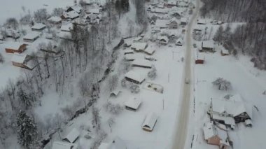 Kışın kırsal alan. Karpatya köyünde kış yolunda giden bir arabanın hava görüntüsü. Kuş bakışı karla kaplı evler.
