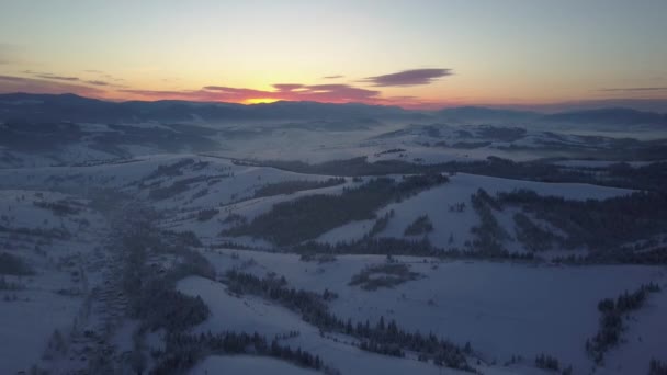 Полет над Карпатами зимой на восходе солнца. Сельский пейзаж зимой с высоты. Вид с воздуха на заснеженную горную деревню . — стоковое видео