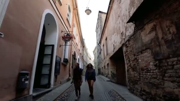 Camine por las antiguas calles de una ciudad europea. Dos jóvenes caminando por las estrechas calles del casco antiguo de Vilna. Dos jóvenes caminan en el casco antiguo de Vilna . — Vídeos de Stock