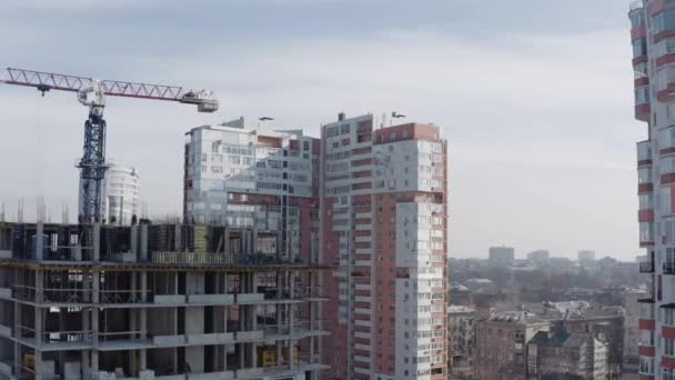 Панорама строительства нового высотного здания для проживания людей. Воздушный кадр строительного крана и рабочих, строящих дом на фоне модернизированных зданий в центре . — стоковое видео