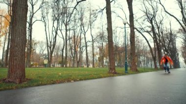 Süslü ceketli spor sakallı Avrupalı adam uzaktan hızlanıyor ve ıslak havada Ukrayna 'nın Harkov kentinde bir parkın arka sokağında teknik dönüş yapıyor. Hafta sonu dışarıda yararlı bir spor hobisi.