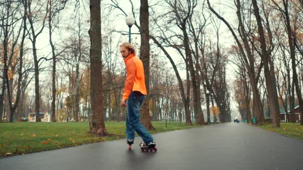 Profesjonalny brodaty rolkarz robi różne trudne triki i zakręty, pokazując aktywną technikę jazdy w alejce parku miejskiego po deszczu na tle drzew na wiosnę. Przydatny czas wolny. — Wideo stockowe