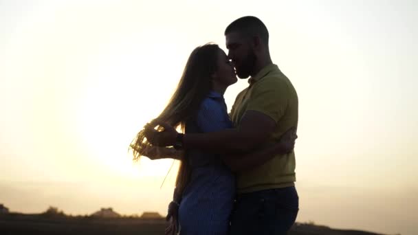 Vista de perto de um jovem casal casado abraçando e beijando na natureza contra o horizonte do céu com o pôr do sol. Uma noite romântica para dois amantes ao ar livre. Data no campo entre as espiguetas . — Vídeo de Stock