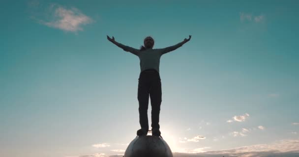 Geïnspireerd actieve man met baard staat op het puntje van de neus van gevechtsvliegtuigen met armen uitgestrekt tegen de hemel en zonsondergang, frontaal zicht vanaf de bodem. Bezoek aan oude militaire vliegtuigen op de luchthaven. — Stockvideo