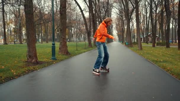 Patinador técnico y experimentado haciendo giros complejos y fintas en patines en un callejón del parque de la ciudad entre los árboles en clima húmedo. Ocio activo hombre barbudo deportivo de vacaciones o fin de semana . — Vídeos de Stock