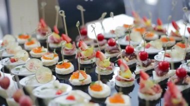 Davetliler için iştah açıcı ve lezzetli düğün atıştırmalıkları, çilek, kiraz, brie peyniri, kırmızı havyar, ananas, limon gibi, sabah şölen salonundaki siyah masa tepsisinde..