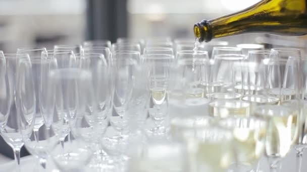 Detailní záběr mnoha elegantních sklenic na stole svatební hostiny, do které se nalévá šampaňské. Číšník ráno naplní svatební sklenice šampaňským v hodovní síni. — Stock video