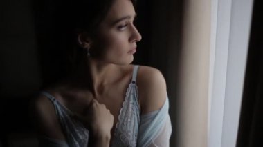 Zarif mavi peignoir giymiş güzel seksi kız üzüntülü bir şekilde pencereden dışarı bakar, omuzlarının üzerinden koşar. Makyajlı, uzun saçlı, iri gözlü esmer, karanlık odada birini bekliyor.