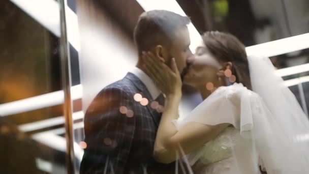 Bröllopspar kysser i en vacker och mysig hiss av Kharkov Palace Hotel, Ukraina. Ung glad brud och skäggig brudgum avskilt sig i en bekväm hiss för kramar och kyssar. — Stockvideo