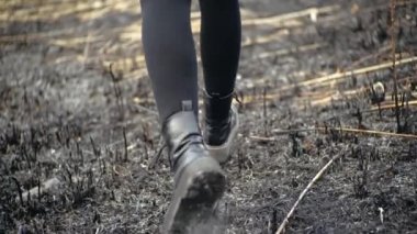 Tozluklu kadın bacakları ve şık siyah yüksek tabanlı ayakkabılarıyla öğleden sonra güneşli havada yanan kül tarlalarının üzerinde koşan sinematik çekim. Küllerin arasında koşan kız.