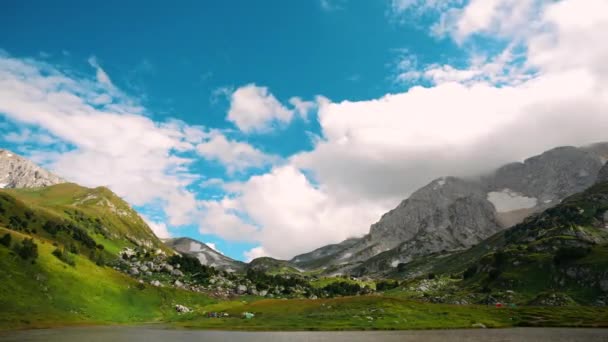 澄んだ空に巨大な飛行雲の下で斜面の石の木と見事なコーカサス山脈の時間の経過。アディジェ州の谷クセノダチ湖を旅行しています。キャンプ観光の概念｜ハイキングアルピニズム — ストック動画
