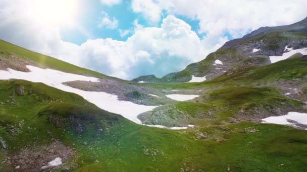 Voo aéreo sobre a beleza Montanha caucasiana com neve coberta por grama verde sob nuvens cúmulos raios de sol arco-íris, Adygea, Rússia. Proteger, reservar, financiar conceito de ecologia mundial. Bela terra . — Vídeo de Stock