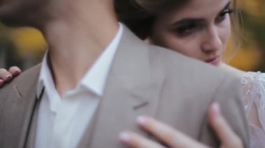 Güzel bir kadın tarafından kucaklanıp okşanan takım elbiseli bir adamın yakın plan görüntüsü. Kız, güvenilir, sorumluluk sahibi bir adamın arkasında dikilip başka tarafa bakıyor..