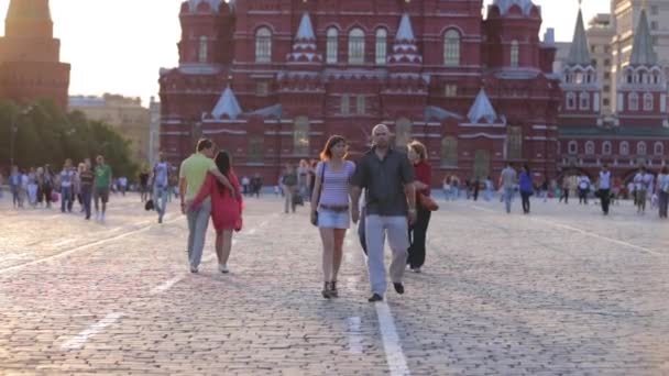 Ryssland, Moskva - 06.05.2020: Främre skott av en folkmassa som går på Röda torget mot bakgrund av den berömda Historiska museet i soligt väder. Man går med en flicka och vågor vid kameran. — Stockvideo