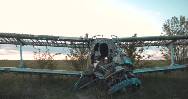 Close-up zicht op de gedemonteerde romp van het oude skelet van de USSR maïsvliegtuig staat in dik gras van overwoekerd veld tegen zonsondergang in slow motion. Sovjet verlaten vliegtuigen voor het vliegen op de luchthaven. — Stockvideo