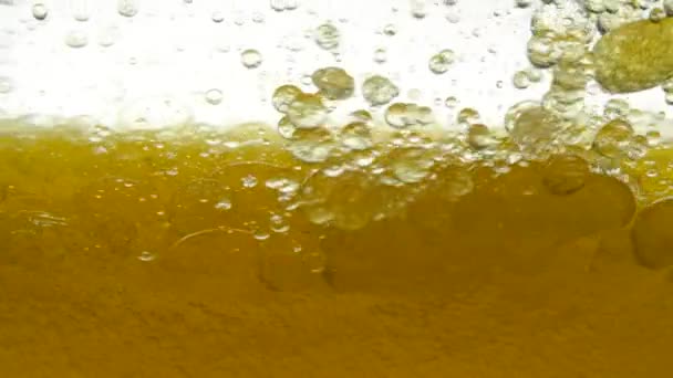 Golden and white background of poured sesame oil and black cumin oil, resulting in air bubbles and bulbs. Close shot of pouring peanut oil and golden walnut oil in container. Close-up of olive oil. — Stock Video