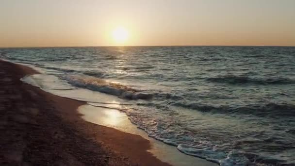 夏の日没と空を背景に砂浜に小さな波を入れ込むの水の上の空中ビュー。朝の夜明けに海沿いの海岸。美しい野生自然保護区. — ストック動画