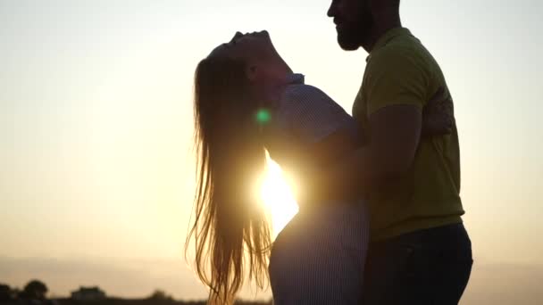 Amare giovane coppia gode di romanticismo e baci affettuosi abbracci in natura. Ragazzo barbuto piega bella ragazza con i capelli lunghi nel campo, sfondo di meraviglioso tramonto, primo piano al rallentatore. Data esterna — Video Stock