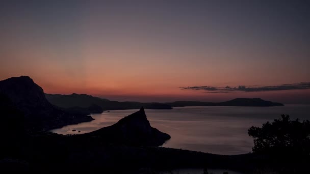 Όμορφη εναέρια λήψη του New World Bay το σούρουπο κάτω από ροζ ουρανό. Πανοραμική άποψη του χρόνου ολίσθησης των βράχων κοντά στη Μαύρη Θάλασσα πριν από την αυγή του ήλιου, Κριμαία. Ωκεανός και βουνά τη νύχτα, κορυφαία θέα. — Αρχείο Βίντεο