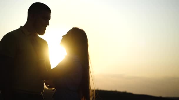 Bella ragazza accarezza il viso del ragazzo barbuto e strofinano il naso al rallentatore da vicino, il tramonto brilla tra di loro la sera d'estate. Romantico appuntamento di giovane coppia appassionata innamorata nella natura all'aperto. — Video Stock