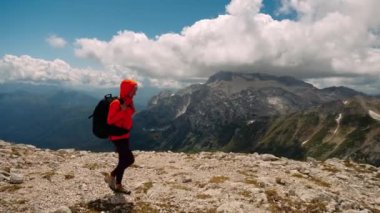 Sırt çantalı aktif kadın turistin tepe noktasını fethettikten sonra aşağı inişi, güzel dağların ve bulutların arka planı. Yürüyüş ve sağlıklı yaşam tarzı.