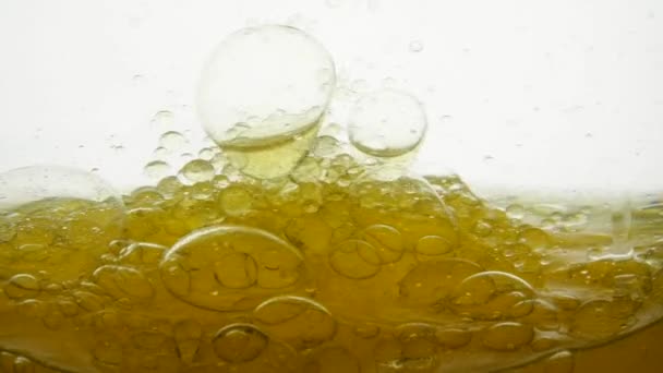 El aceite amarillo girasol se mezcla con agua, no se disuelve. Las bombillas de aire de burbujas flotan en líquidos creando patrones, texturas y fondos elegantes. Toma en cámara lenta de Líquido de Aceite de Verter. Vitamina E saludable — Vídeos de Stock