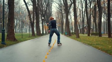 Sakallı Avrupalı adam şehir parkının rahat sokağındaki özel konilerin yardımıyla paten kayma tekniğini eğitir ve biler. Profesyonel scooter daireleri ve baharda antrenman konileri arasında dönüşler.