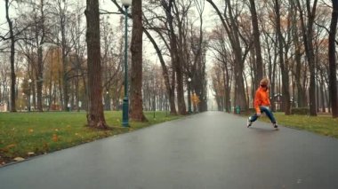 Turuncu ceketli sportif sakallı Avrupalı erkek patenci Central City Park 'ın arka sokağında karmaşık ve teknik hareketler ve buz pateni yapıyor. Sağlıklı bir yaşam tarzı ve dışarıda boş vakitleri var..