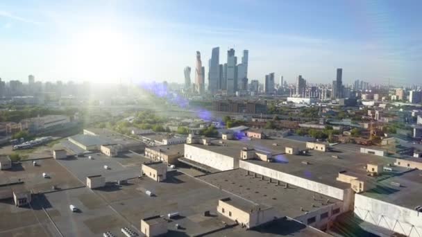 Luchtfoto uit de verte van wolkenkrabbers en kantoorgebouwen, residentiële gebouwen van Moskou tegen de achtergrond van heldere verblindende zon met horizon en blauwe hemel in de herfst, Rusland. Top uitzicht op het centrum. — Stockvideo